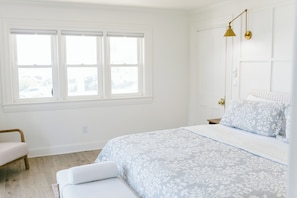 Unwind in this airy king bedroom with elegant linens, soft seating, and large windows that fill the space with natural light. A peaceful retreat just steps from Boothbay Harbor's shops, restaurants, and scenic waterfront.
