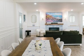 Gather in this open-concept shared space featuring a large dining table, elegant fireplace, and smart TV. Ideal for relaxing, dining, or connecting with fellow travelers during your stay in charming Boothbay Harbor.