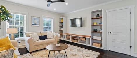 Living Room with built in shelving, ceiling fan, queen pull out couch and TV