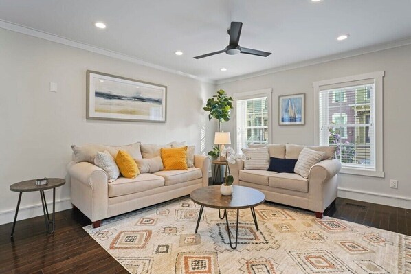 Living Room with built in shelving, ceiling fan, queen pull out couch and TV