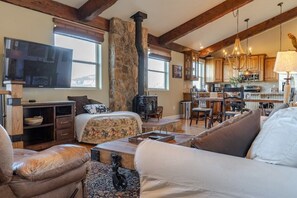 Step inside to a warm, inviting living space! The rustic decor, wood beams, and cozy stone fireplace create a charming ambiance. You will love relaxing here, with plenty of natural light streaming through large windows showcasing stunning views. (Main living area)