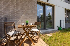 A quaint outdoor patio with a wooden table and chairs, set against a brick facade, ideal for enjoying meals or relaxing outdoors.