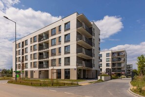 A modern apartment building with large windows, clean lines, and well-maintained greenery, presenting a sleek architectural design.