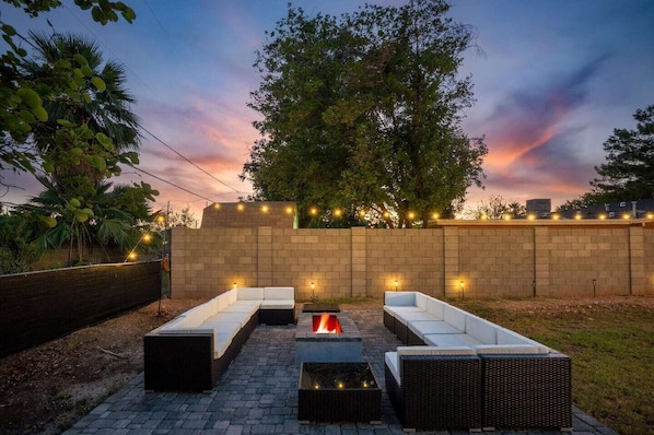 Spacious outdoor lounge area with comfortable seating around a cozy fire pit, perfect for evening gatherings under the Arizona sky.