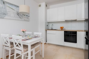 A contemporary open-plan kitchen equipped with white cabinets, a sleek countertop, and modern appliances.
