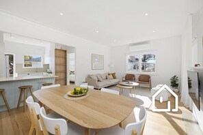 Open plan main living area with dining table for 6 and 3 bar stools 