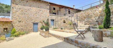 Grand Gîte / Maison de Vacances avec spa - La Maison de Famille du Pourron à Villechenève (Rhône, Monts du Lyonnais) : la cour intérieure composée de plusieurs espaces.