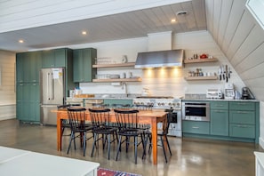 Stylish kitchen with sleek appliances, open shelving, and a warm, inviting dining area