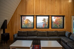 Cozy living space with a panoramic mountain view framed by large picture windows - a perfect spot to relax and unwind after a long day on the slopes