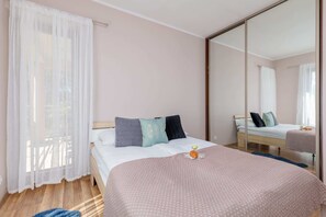 A cozy bedroom with a soft double bed, neutral-toned bedding, and floor-to-ceiling curtains for privacy and comfort.