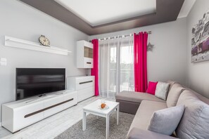 A modern and spacious living area with a comfortable gray sofa, bright pink accents, and a stylish coffee table, creating a vibrant and welcoming atmosphere.