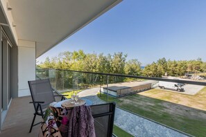 A spacious balcony with outdoor seating and a relaxing view of the surrounding green landscape.