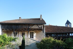 Maison vue du jardin fleuri fermé par un portail extérieur