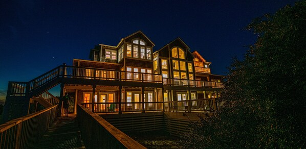 A grand oceanfront estate, beautifully lit under the starry sky.