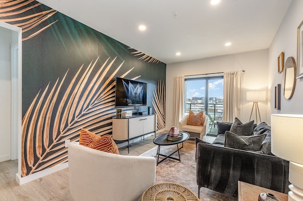 Warm and inviting living space featuring a large flat-screen Smart TV and designer furnishings with a spacious balcony.