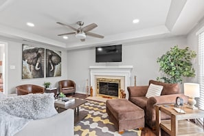 Secondary safari themed living room with a flat screen Roku TV, ceiling fan and queen sized pull-out couch.