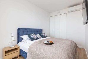  A cozy bedroom with a double bed, white walls, and a modern design.