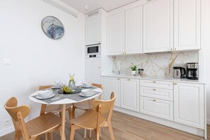 A modern kitchen with white cabinets, a round dining table, and a bright atmosphere.