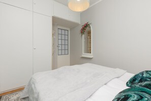 Another perspective of the bedroom, showcasing a neatly arranged bed, mirrored wardrobe, and soft decor.


