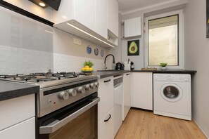 A modern kitchen with a gas stove, oven, and washing machine, offering convenience and practicality.


