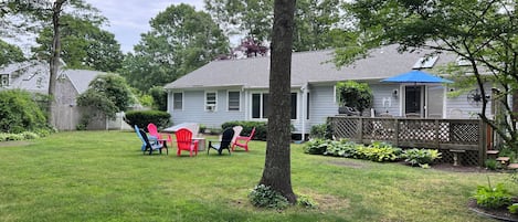 View of backyard including Adirondack chairs, and fire pit.