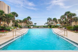 Swimming Pool with onsite Bathrooms, Chaise Loungers, Tables & Chairs, surrounded by Lush Landscaping