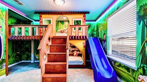 Jungle-themed kids' room with loft playhouse, slide, and cozy bunk beds!
