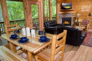 The cabin's open-concept dining and living area has beautiful views through the wall of windows of the hill-side forest.