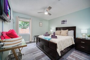 Cozy guest bedroom with queen bed, smart TV, and peaceful garden views.