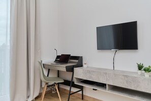 A cozy living area with a wall-mounted TV, a stylish console, and a workspace in the corner for added functionality.