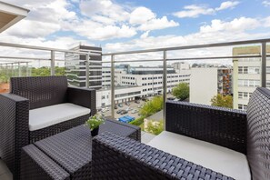 A private balcony with comfortable rattan seating and a stunning view of the surrounding cityscape.