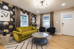 This stylish living room features bold décor, a comfy green sofa, and plenty of natural light for a welcoming vibe.