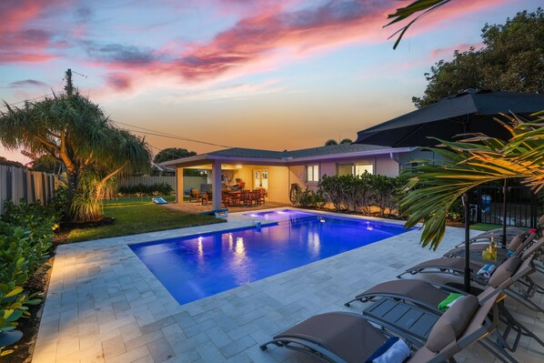 Our backyard oasis features a refreshing pool adjacent to the covered terrace, where you can also enjoy a game of cornhole or practice your putting skills on the green, creating endless opportunities for enjoyment and fun.