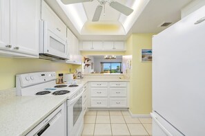 Fully equipped kitchen with white cabinetry, modern appliances, and ample counter space.