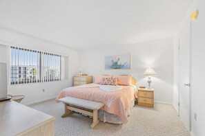Master bedroom featuring a king-size bed, soft pastel decor, and natural light.