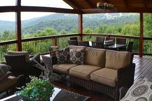 Scenic deck lounge with wicker seating, a dining area, and breathtaking mountain views.