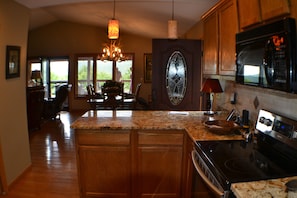 Modern kitchen with granite countertops, wooden cabinetry, and a stylish glass-paneled door.