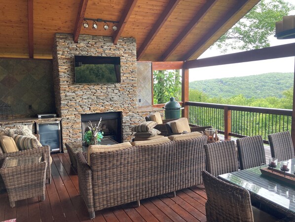 Scenic outdoor lounge with wicker seating, a stone fireplace, and breathtaking mountain views.