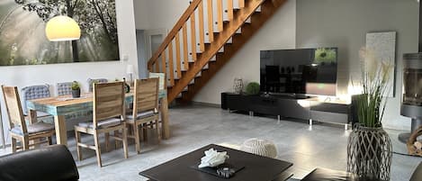 Ferienhaus-Blick ins Wohnzimmer mit Kamin, großem Smart TV - Fernsehr