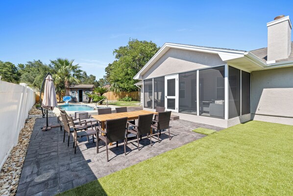 Large private back yard with a pool, dining table, putting green and loungers. 