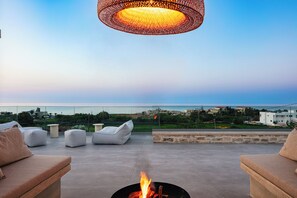 Unwind and savor breathtaking views of both the sea and the mountains, from our roof terrace, featuring a U-shaped seating area and a cozy fire pit for unforgettable gatherings