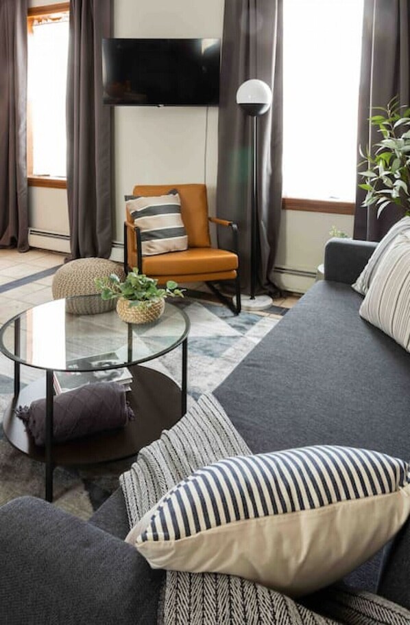 Downtown New Haven Vacation Rental Near Yale – Spacious living area complete with a full kitchen, smart TV, and a sofa bed for two additional guests. Enjoy seating for four, large bright windows with blackout curtains, and A/C for a comfortable, convenien