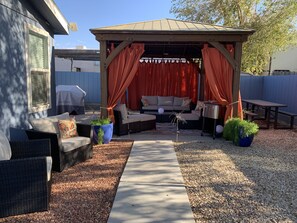 Backyard gazebo/lounge with bbq grill, ice chest, bar cart, table & fire pit.