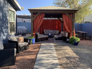 Backyard gazebo/lounge with bbq grill, ice chest, bar cart, table & fire pit.
