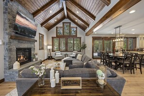 This living room is a vision of rustic elegance, featuring a towering stone fireplace, plush seating, and natural wood beams