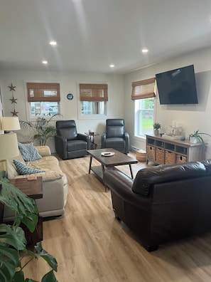Living room with couches, recliners, TV, Alexa, DVD player with some movies.