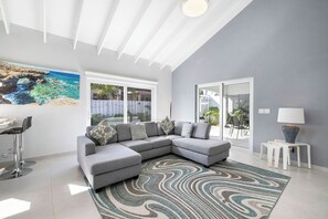 The spacious living area features a calming interior color scheme, a high ceiling, and a comfortable sofa, making it ideal for relaxation.