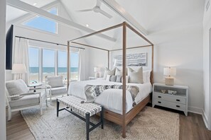Luxurious primary suite with comfortable king bed, ocean view, TV and private bathroom