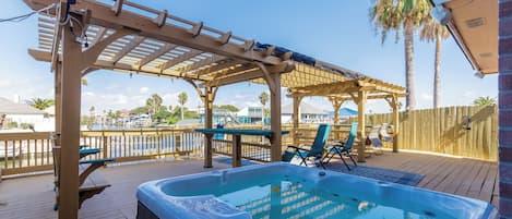 Large private deck with waterfront views, lounge chairs and hot tub