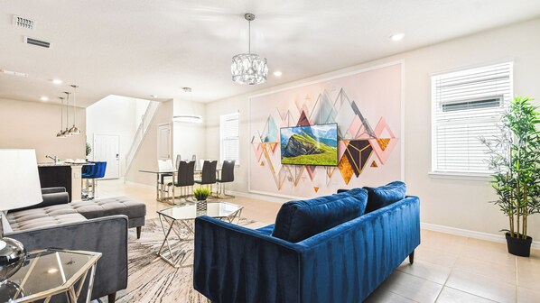 Movie nights made easy! This living room features a large flat screen TV  mounted on the wall, comfy couches, and colorful chairs for movie marathons!